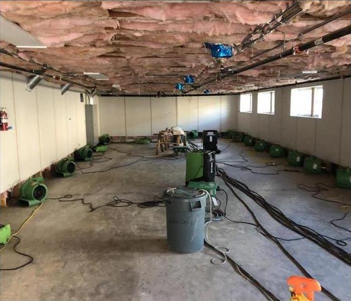 large commercial space with ceiling removed down to insulation. SERVPRO dryers around room
