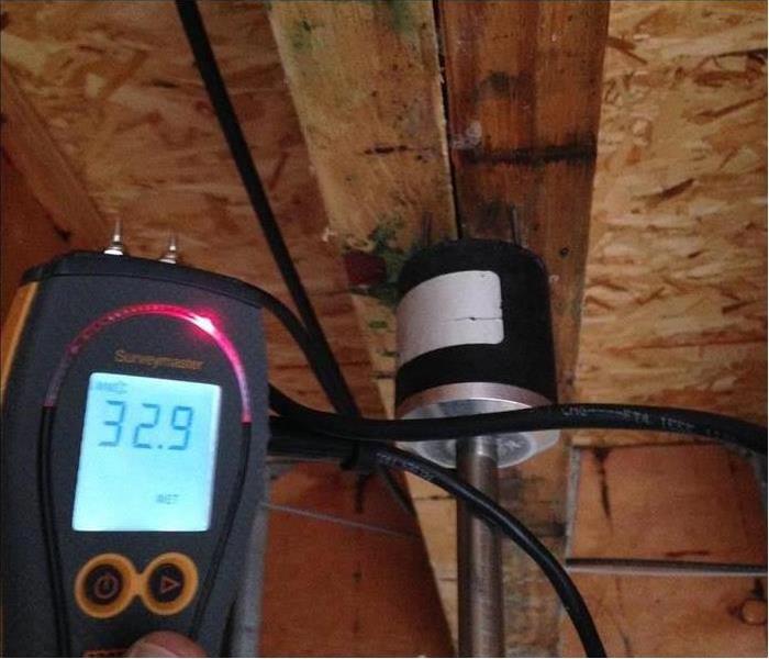 Moisture meter showing a reading and wood beams